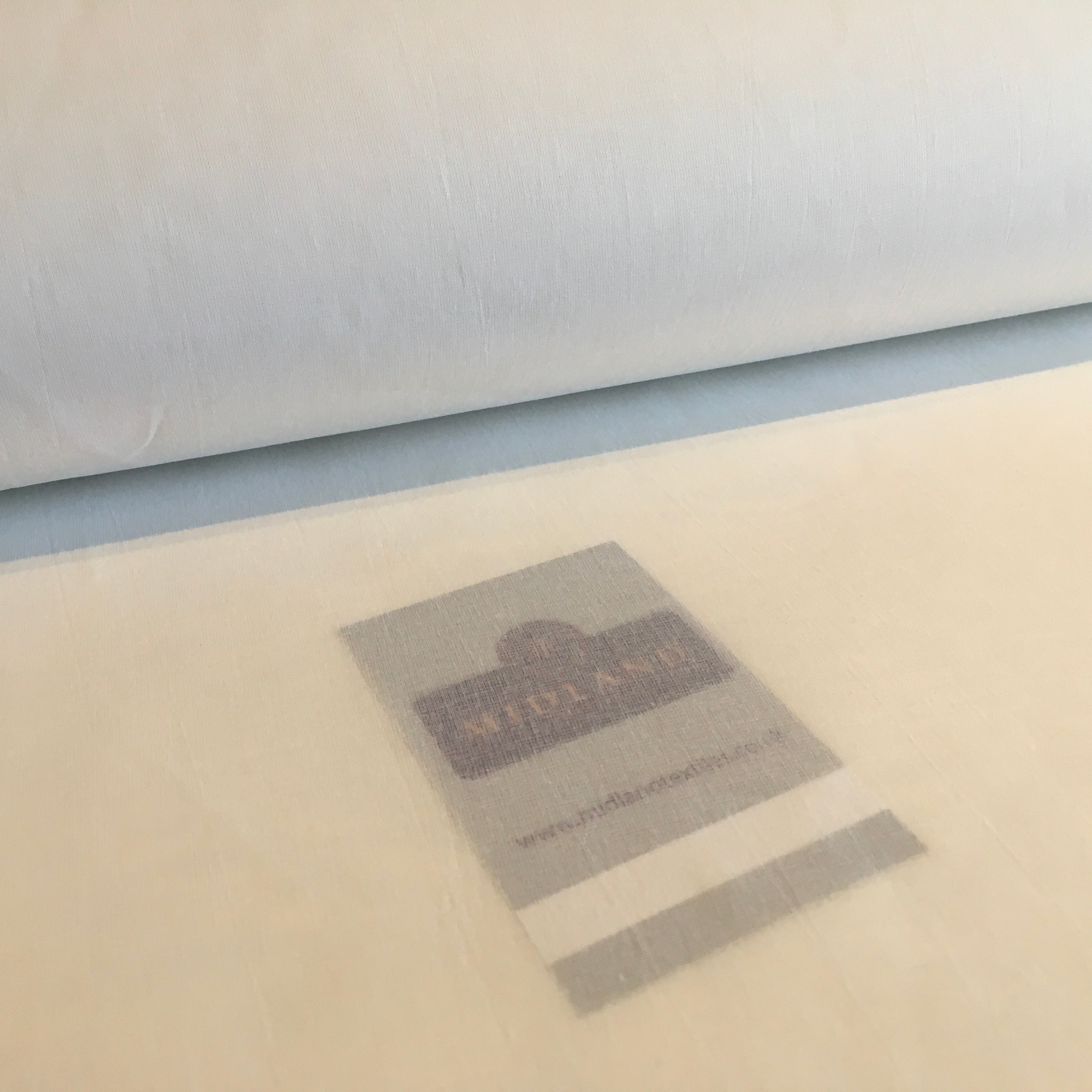 Roll of fabric with a label on a beige surface